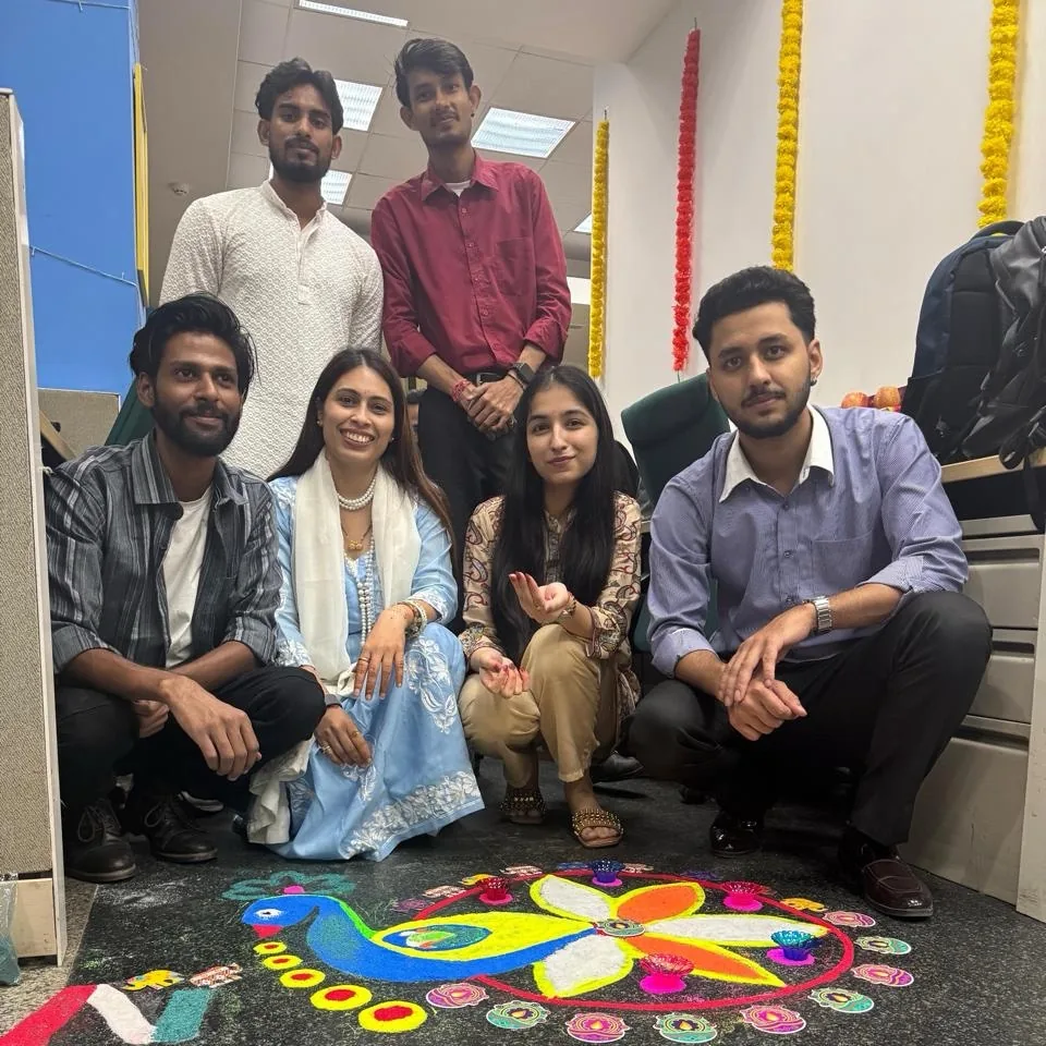 Anviam team members beside a hand-painted Diwali rangoli